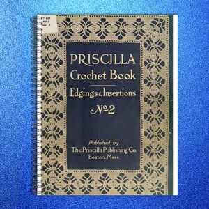 May include: A spiral-bound book titled Priscilla Crochet Book Edgings & Insertions No 2, published by The Priscilla Publishing Co. Boston, Mass. The cover features a dark blue center panel with cream-colored crochet lace border patterns.