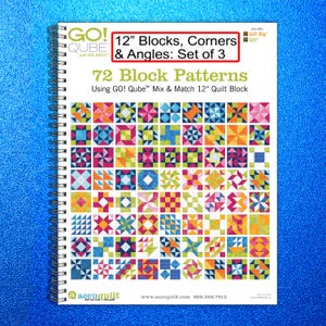 May include: A spiral-bound book titled "12" Blocks, Corners & Angles: Set of 3" with colorful quilt block patterns. The cover features the text "72 Block Patterns" and the AccuQuilt logo. The background is a bright blue.