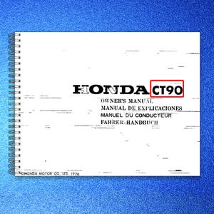 May include: A white spiral-bound Honda CT90 owner's manual with black text. The cover displays the text HONDA CT90, OWNER'S MANUAL, MANUAL DE EXPLICACIONES, MANUEL DU CONDUCTEUR, FAHRER-HANDBUCH, and HONDA MOTOR CO., LTD. 1976 in a horizontal layout.