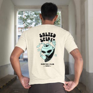 Salted Spirit Coconut Surfing T-Shirt, Retro Beach Streetwear for Surf Lovers, Unique Quirky Surf Gift, Summer Ocean Vibes Graphic Tee