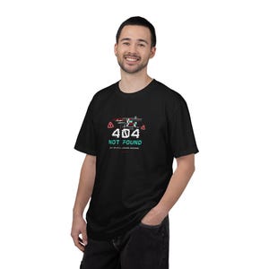 May include: Black t-shirt with a pixelated graphic featuring the text "404 NOT FOUND" in white and teal. The design includes red warning triangles. The shirt also has the text "BUT I'M STILL LOOKING AWESOME".