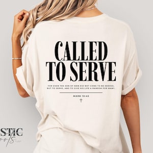 Peut inclure: T-shirt crème avec l'inscription "CALLED TO SERVE" en lettres noires grasses. En dessous, une citation de Marc 10:45 et une croix. Le logo de la marque "RUSTIC roots" est en bas.