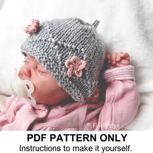 May include: A PDF knitting pattern for a gray baby hat with pink flower embellishments. The pattern includes instructions to make the hat yourself. "PDF PATTERN ONLY. Instructions to make it yourself. This is not an actual finished hat." is written below the image.
