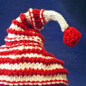 K&ouml;nnte beinhalten: Eine rot-wei&szlig; gestreifte Strickm&uuml;tze mit einem wei&szlig;en Bommel oben.