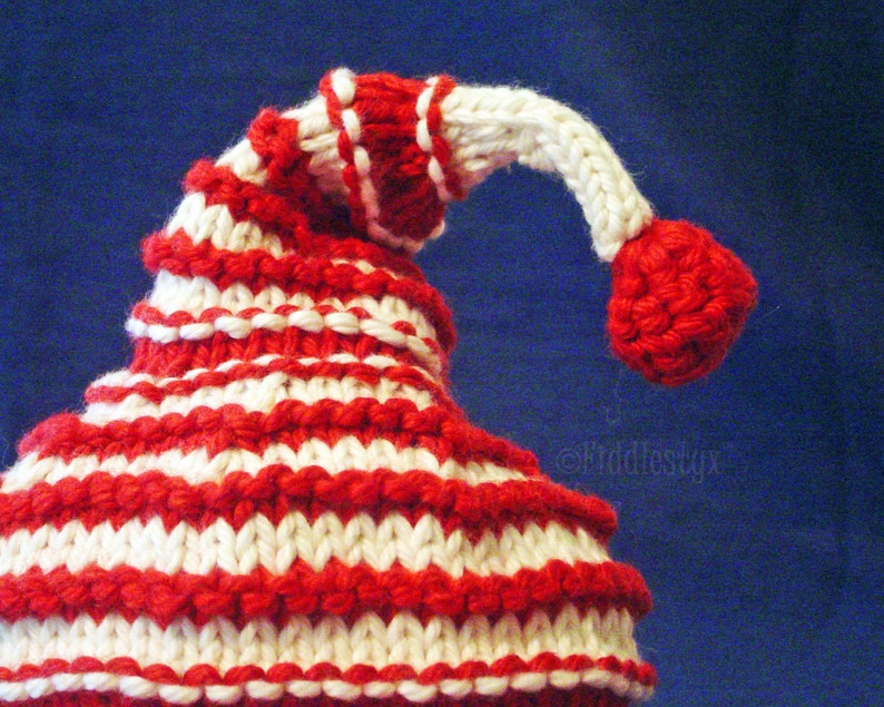 K&ouml;nnte beinhalten: Eine rot-wei&szlig; gestreifte Strickm&uuml;tze mit einem wei&szlig;en Bommel oben.
