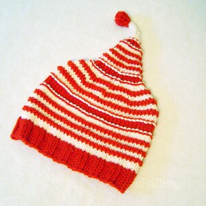 K&ouml;nnte beinhalten: Gestrickte rote und wei&szlig;e gestreifte M&uuml;tze mit einem Bommel oben.