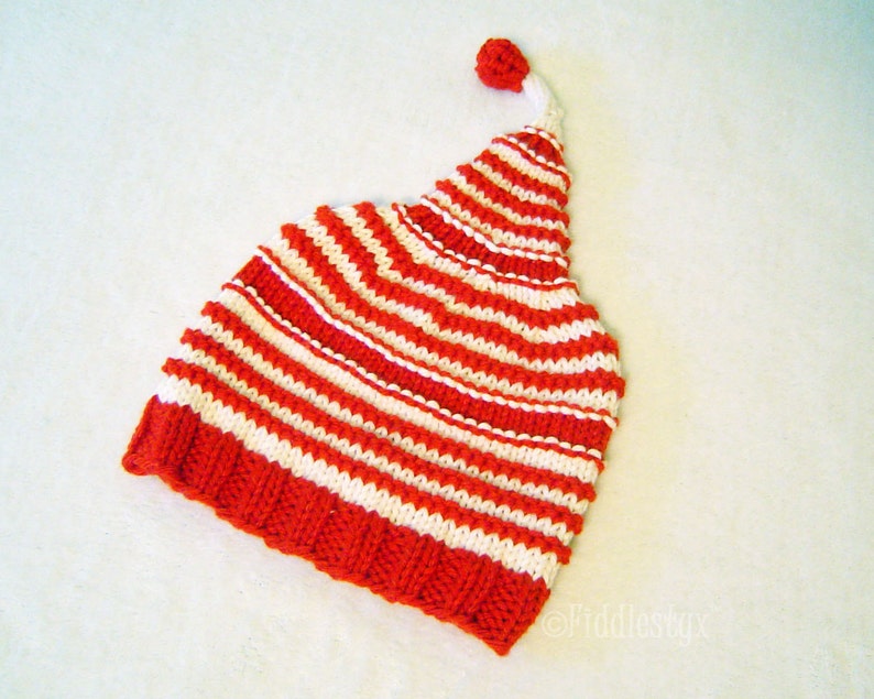 K&ouml;nnte beinhalten: Gestrickte rote und wei&szlig;e gestreifte M&uuml;tze mit einem Bommel oben.