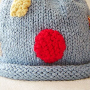 May include: A blue knitted hat with a red, yellow, and white polka dot pattern.