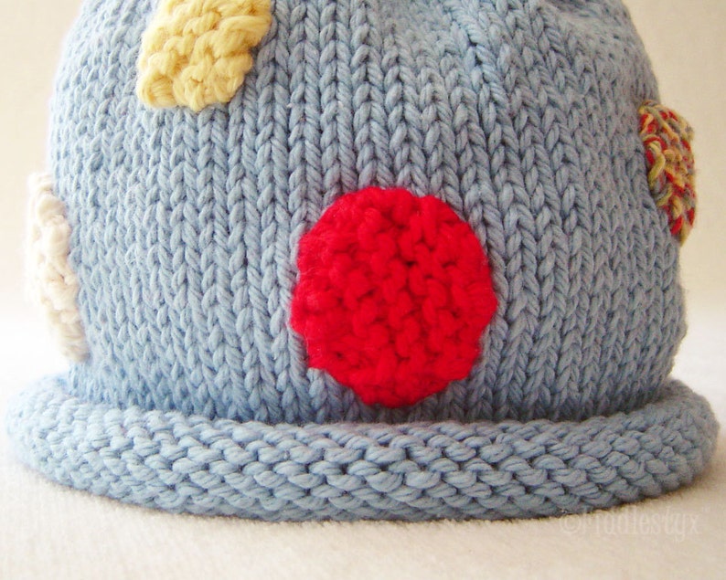 May include: A blue knitted hat with a red, yellow, and white polka dot pattern.