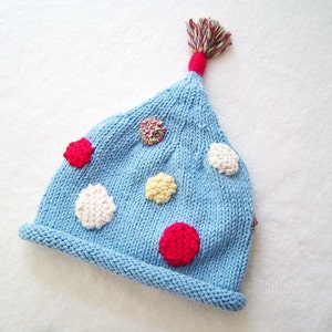 May include: A light blue knitted hat with a pom-pom on top and colorful polka dots.