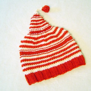 K&ouml;nnte beinhalten: Rote und wei&szlig;e gestreifte Strickm&uuml;tze mit einem kleinen roten Bommel oben.