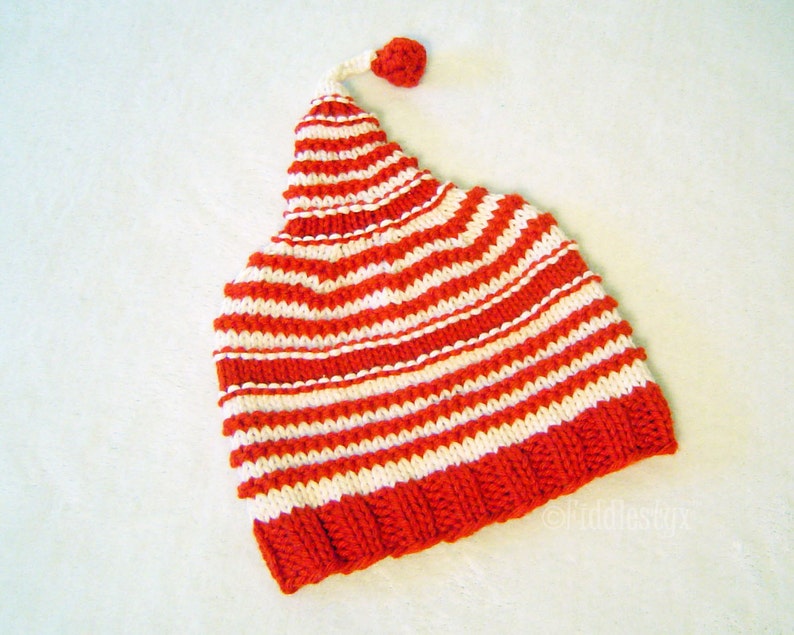 K&ouml;nnte beinhalten: Rote und wei&szlig;e gestreifte Strickm&uuml;tze mit einem kleinen roten Bommel oben.