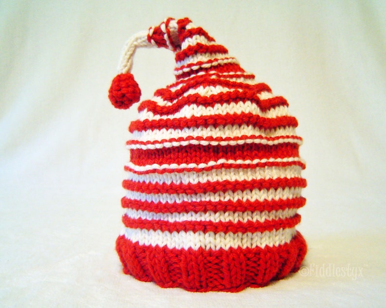 K&ouml;nnte beinhalten: Rote und wei&szlig;e gestreifte Strickm&uuml;tze mit einem wei&szlig;en Bommel oben.