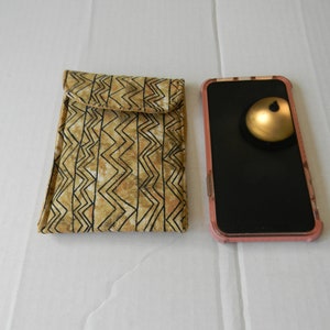 Peut inclure: Une coque de téléphone en tissu à motifs marrons et noirs à côté d'une coque de téléphone rose avec un écran noir.