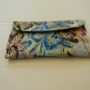 May include: A clutch purse with a floral pattern in shades of blue, brown, and white.