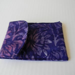 Peut inclure: Un portefeuille en tissu à motif floral violet et rose avec une fermeture à rabat.