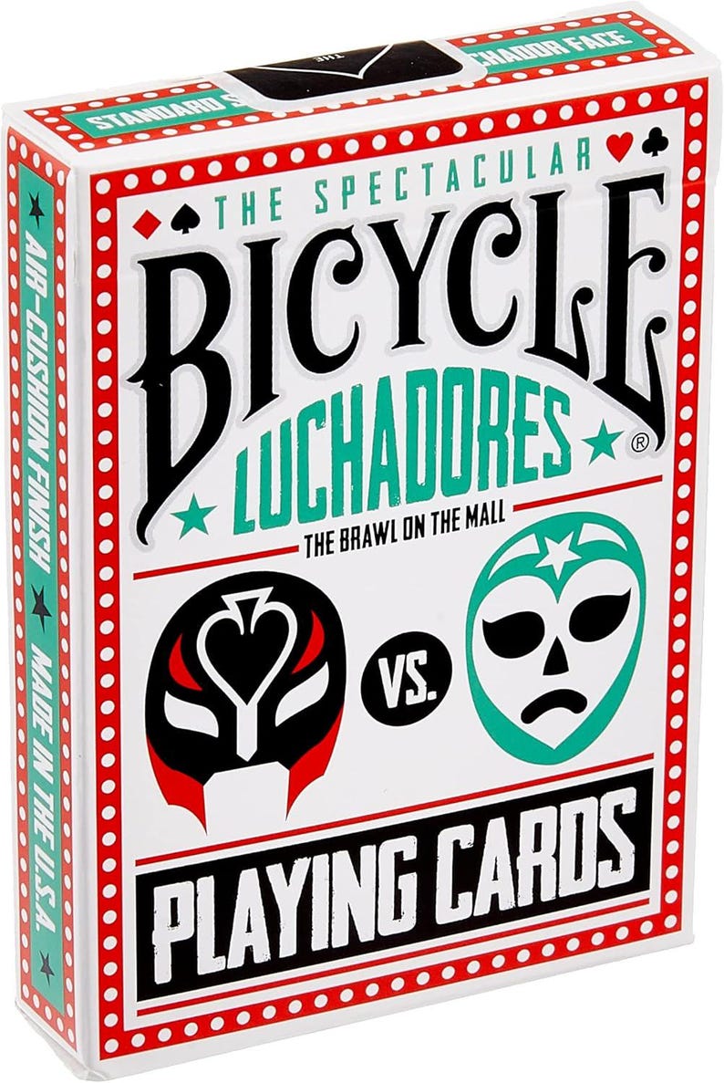 Op de afbeelding: Een deck Bicycle speelkaarten met een Luchador-thema. De doos heeft een rood en zwart masker aan de linkerkant en een groen masker aan de rechterkant. De tekst op de doos luidt "The Spectacular Bicycle Luchadores The Brawl on the Mall".