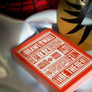 Op de afbeelding: Een rood deck speelkaarten met de woorden "Brawl on the Mall" en "Fun" gedrukt op de voorkant. Het kaartspel ligt op een witte en zwarte stoffen achtergrond.