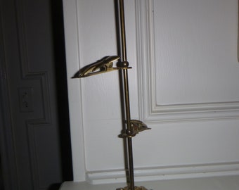 May include: A gold metal stand with three clips and a decorative base. The stand is designed to hold photos or other items.