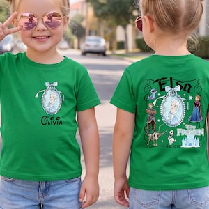 May include: A bright green t-shirt featuring a small oval cameo of Elsa on the front chest with the name Olivia below. The back displays a large graphic with Elsa, Anna, Kristoff, Sven, Olaf, and the Frozen logo with the text Est. 2013.