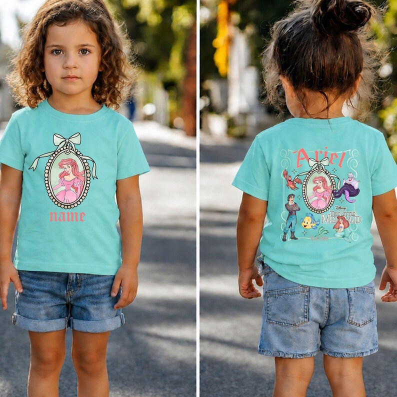 Puede incluir: Una camiseta turquesa con una imagen de dibujos animados de una princesa con un vestido rosa dentro de un marco ovalado con un lazo. El nombre "Name" est&aacute; impreso debajo. La parte posterior de la camiseta tiene la imagen de la princesa y otros personajes.