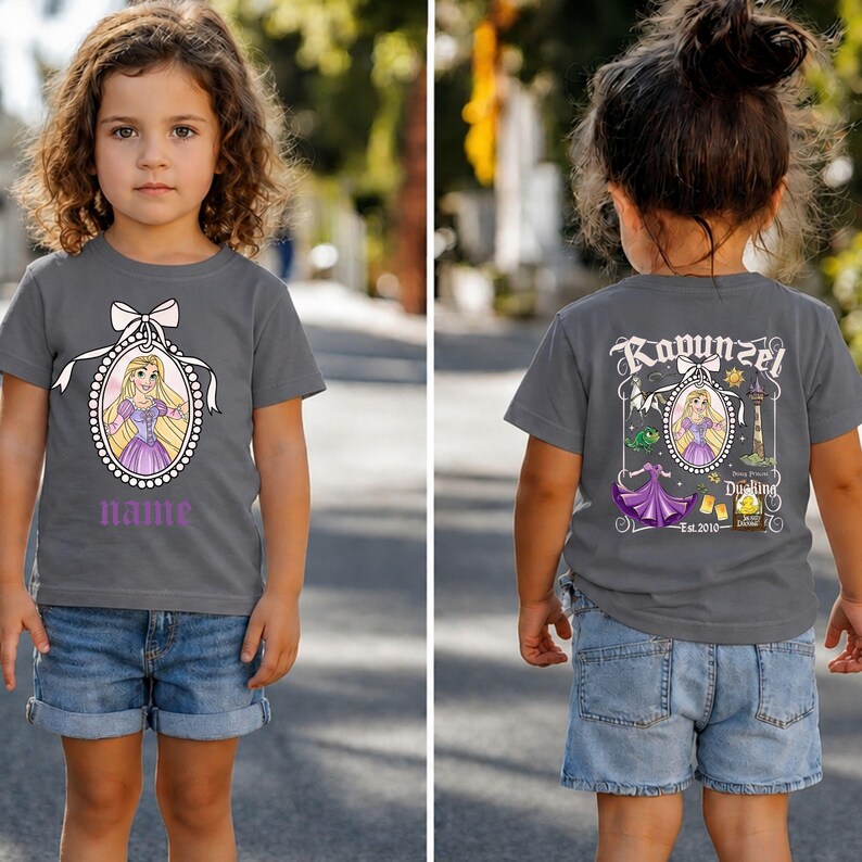Puede incluir: Camiseta gris con una imagen de dibujos animados de una princesa en un marco ovalado y un lazo. La palabra "name" est&aacute; impresa debajo. La parte trasera de la camiseta dice "Rapunzel" con una imagen similar.