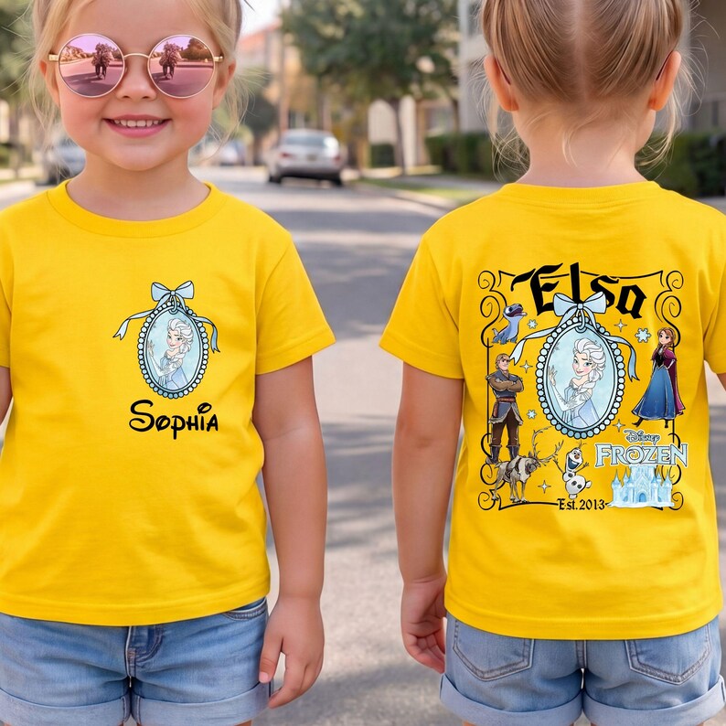 May include: A bright yellow t-shirt featuring a small oval graphic of Elsa on the front with the name Sophia printed below. The back displays a larger Frozen-themed design with Elsa, Anna, Kristoff, Olaf, Sven, and the text Elsa and Disney Frozen.