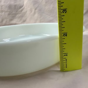 May include: A pale green oval baking dish with a smooth, glossy finish. The dish is approximately 2 inches deep, as measured by a yellow ruler. The dish has a simple, classic design.