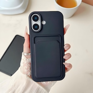 May include: A dark navy blue phone case with a cardholder pocket. The case has a smooth finish and features a dual-lens camera cutout. The cardholder is stitched onto the case. The phone case is designed to protect the phone.