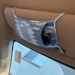 May include: A blue and white crocheted car visor organizer with sunglasses inside.