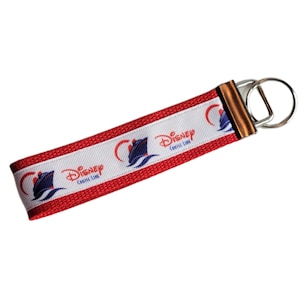 May include: Red and white key chain with a white ship and the text "Disney Cruise Line" repeated on the strap. The key chain has a silver key ring.