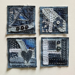 May include: Four blue denim squares with different patchwork designs and various buttons. Each square has a different pattern of stitching and fabric.
