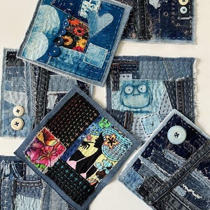 May include: A collection of square fabric patches featuring denim scraps, intricate hand-stitched embroidery, colorful printed textile inserts, and various buttons. The designs include a heart, a stylized owl, and a silhouette figure with floral accents.