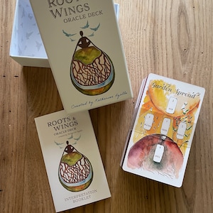 May include: A Roots & Wings Oracle Deck with a guidebook and a card spread layout. The deck features watercolor illustrations of a person sitting inside a tree with roots and wings. The card spread layout shows a garden with a sun, water, seed, soil, and weeds.