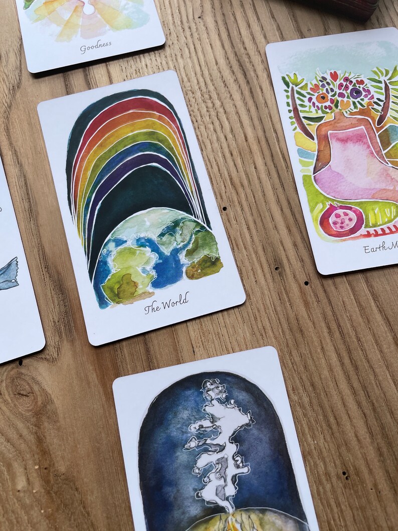 May include: A watercolor illustration of the world with a rainbow arching over it. The card is titled "The World".