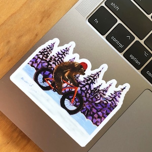 May include: A brown bear wearing a red helmet rides a bicycle through a purple and white forest. The bear is wearing a red helmet and has a white handlebar mustache. The bicycle has a red frame and black tires.