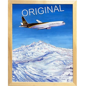 May include: A painting of a UPS airplane flying over a snow-capped mountain range. The painting is framed in a light wood frame and signed "Sundtmeier 2018" in the bottom right corner. The title "ORIGINAL" is written in white letters across the top of the painting.