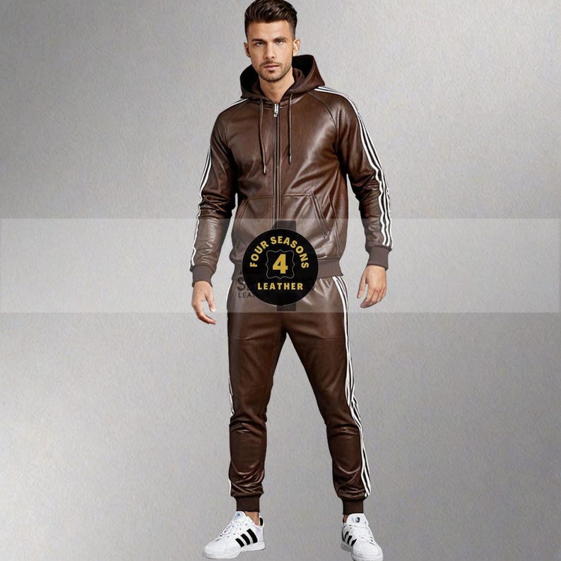 May include: Brown leather tracksuit with white stripes on the sleeves and legs. The jacket has a hood and a zipper. The pants are fitted. The tracksuit is worn with white sneakers.