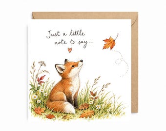 May include: A square greeting card featuring a watercolor illustration of a small orange fox sitting in a grassy field with daisies and fallen autumn leaves. The text reads Just a little note to say... with a small heart above the fox's head.