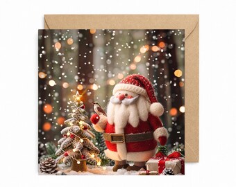 May include: A square greeting card featuring a felted Santa Claus figure with a white beard, red hat, and red coat, standing next to a small decorated Christmas tree, a gift box, and a tiny bird, set against a snowy, bokeh-lit forest background.