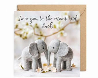 May include: A greeting card with a light brown envelope. The card features two gray felt elephants with trunks touching, surrounded by small flowers. The text "Love you to the moon and back" is written in cursive.