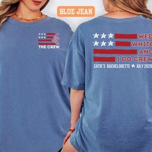 May include: Two blue jean-colored t-shirts with matching graphics. The front of the shirt has a small graphic of a flag with the text "THE CREW". The back of the shirt has a larger flag graphic with the text "WED WHITE AND I DO CREW CATIE'S BACHELORETTE JULY 2025".