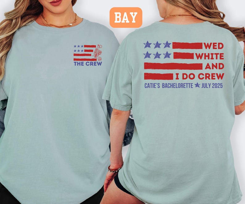 May include: Light blue t-shirt with a red, white, and blue flag design. The front of the shirt says "THE CREW" and the back says "WED WHITE AND I DO CREW CATIE'S BACHELORETTE JULY 2025".