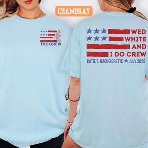 May include: Light blue t-shirts with a patriotic design. The front of the shirt features a red, white, and blue graphic with the text "THE CREW." The back of the shirt has a similar design with the text "WED WHITE AND I DO CREW CATIE'S BACHELORETTE JULY 2025."