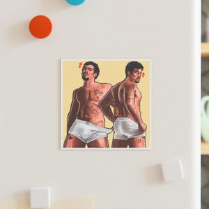 May include: Square magnet featuring an illustration of two shirtless figures in white briefs. The figures are posed in front of a yellow background, with small red hearts above their heads. The artwork has a stylized, artistic appearance.
