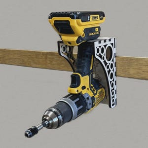 May include: A yellow and black cordless drill with a matching battery pack is mounted on a white and black decorative wall holder. The drill is attached to a wall with a wooden beam.