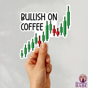 May include: A sticker with the text "BULLISH ON COFFEE" above a green and red stock chart graphic. The sticker is held by a hand with a gold ring. The Investment Babe logo is in the bottom right corner.