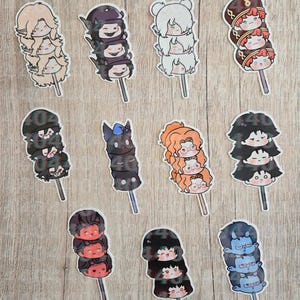 May include: A collection of eleven sticker designs, each featuring three stacked chibi-style character heads on a stick, resembling dango. The characters display various hair colors, including blonde, black, white, red, orange, and blue, with distinct facial expressions.