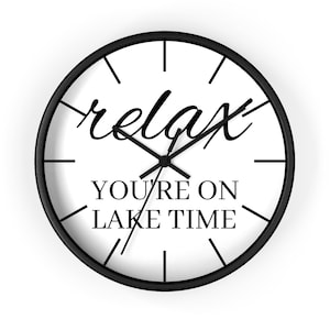 May include: Black and white wall clock with black hands and a white face. The clock face has the text "relax" in a cursive font and "you're on lake time" in a sans-serif font.
