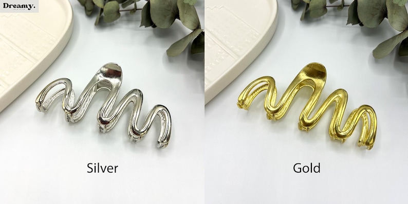 May include: Silver and gold-colored hair clips with a wavy design. The silver clip is on the left, and the gold clip is on the right. The word "Silver" is below the silver clip, and the word "Gold" is below the gold clip.